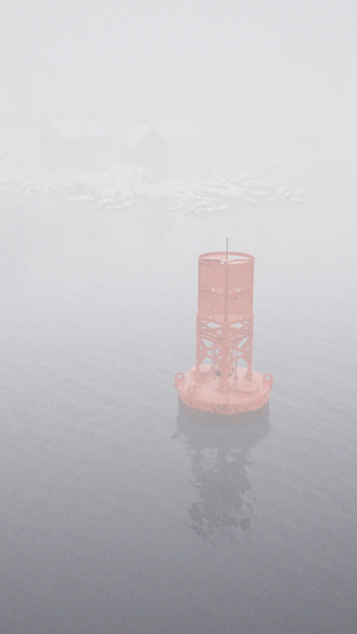 Foggy day with a solitary buoy standing in calm waters