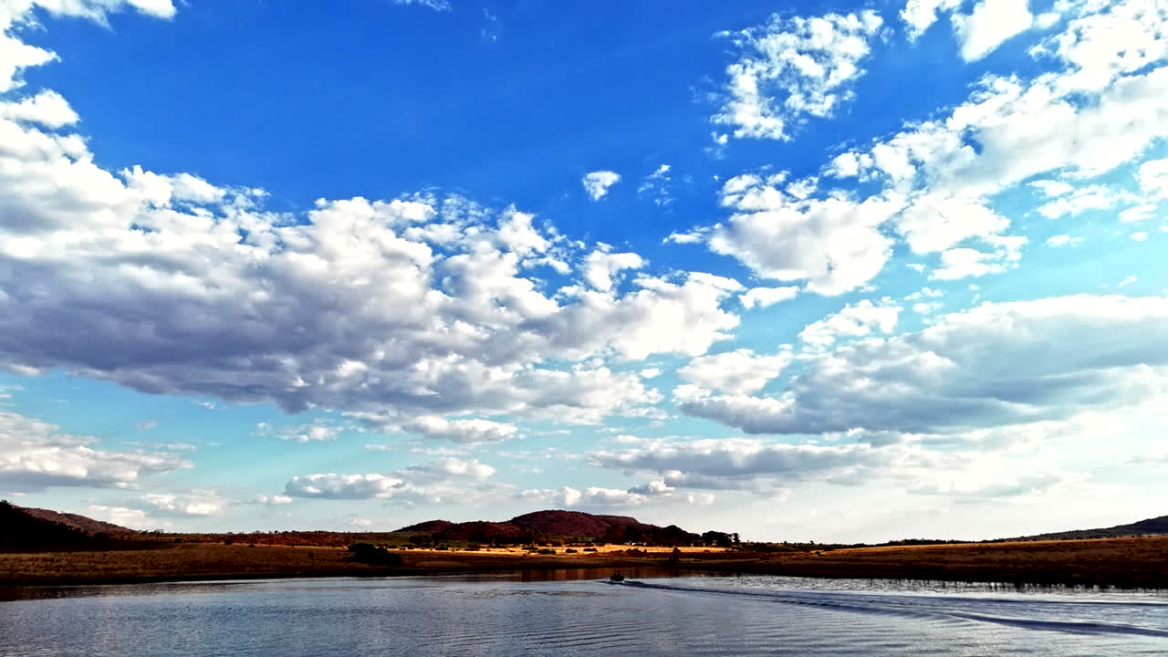 Silhouette of boat cruising on dam with impressive cloudscape in blue sky
