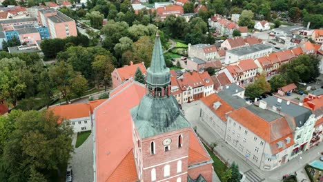 Ein-Kirchturm-Vor-Der-Kulisse-Einer-Malerischen-Stadt,-Gesehen-Von-Einer-Drohne-An-Einem-Herbsttag