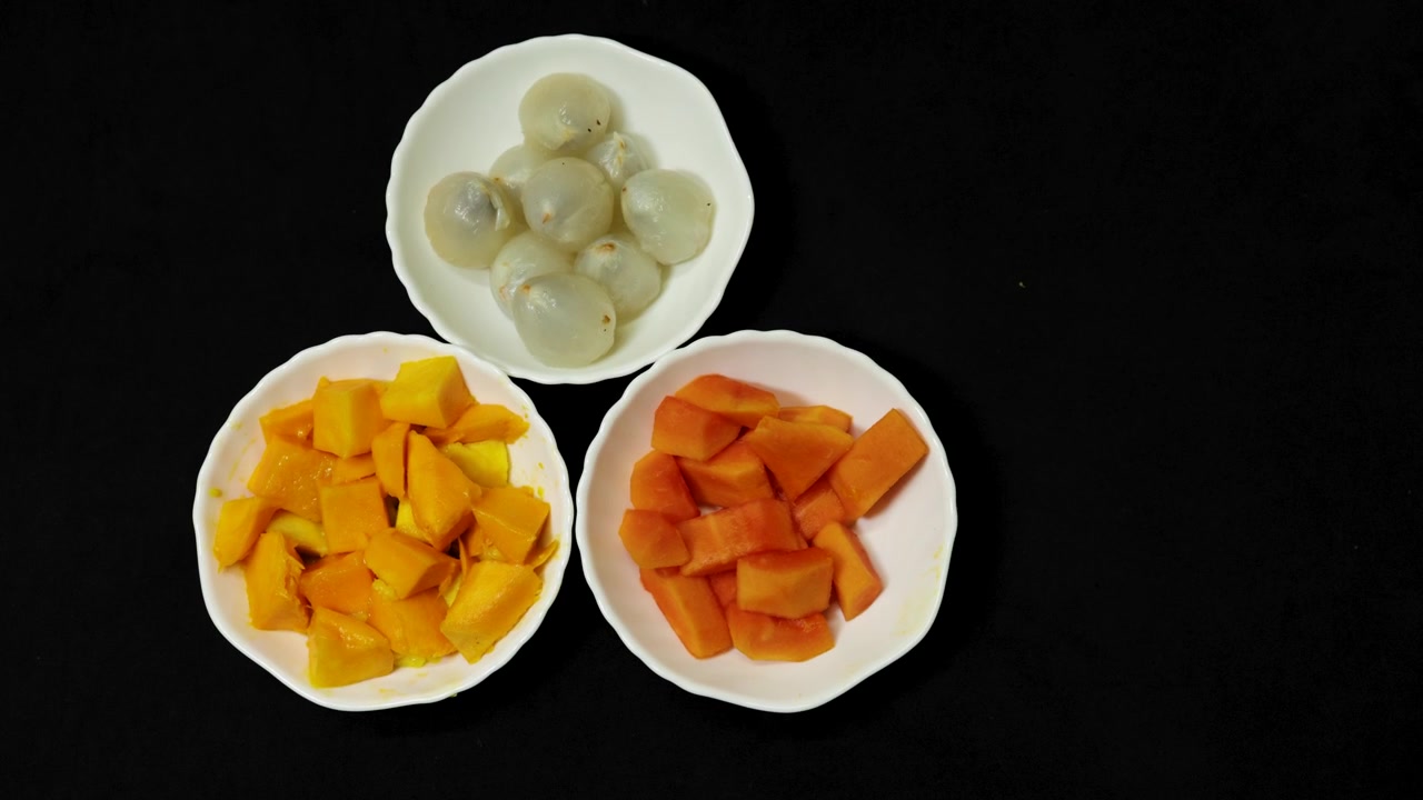 Piatto di frutta fresca con mango, papaya e litchi che mostra colori naturali vivaci.