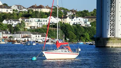 a red and white sailboat anchored on the tamar river near saltash, cornwall