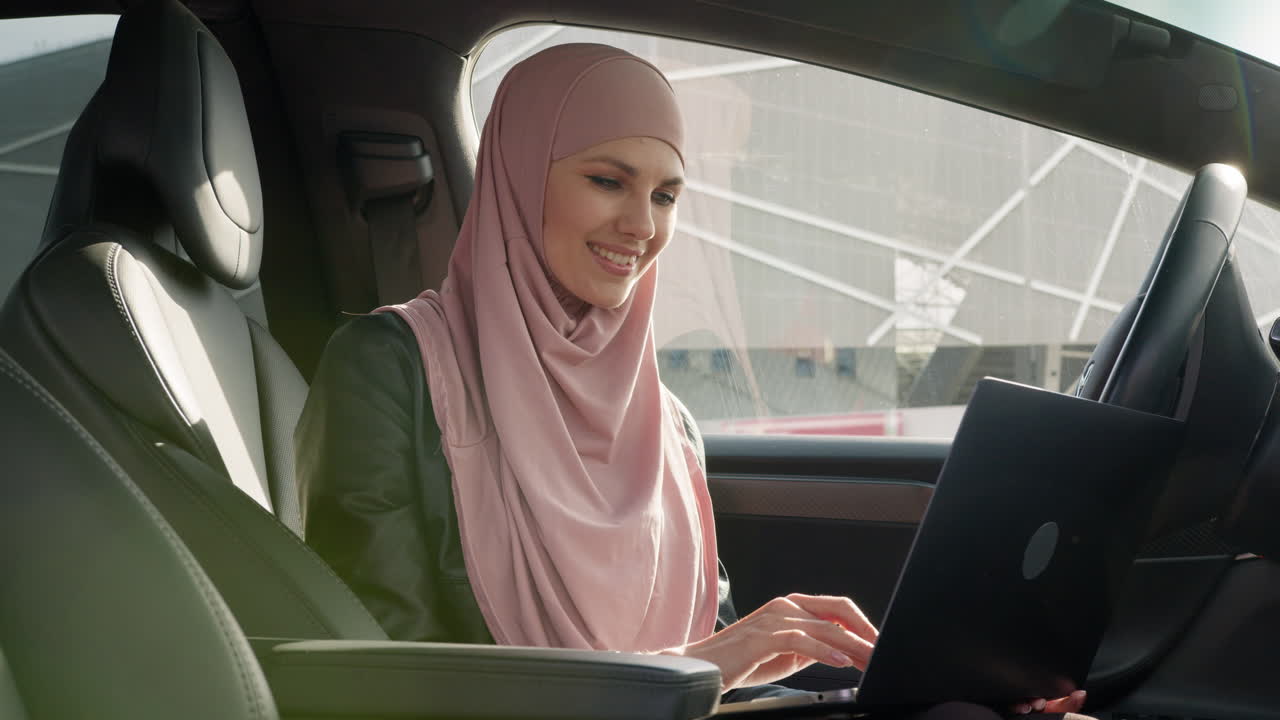 Donna di affari che lavora ad un computer portatile in un'automobile