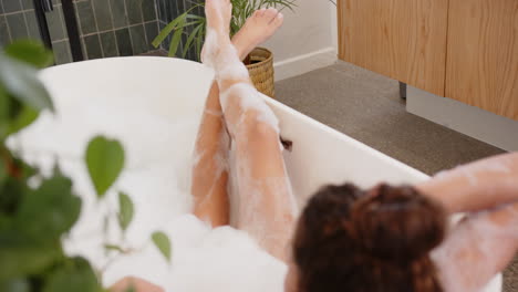 relaxing in bathtub, woman enjoying bubble bath with legs crossed
