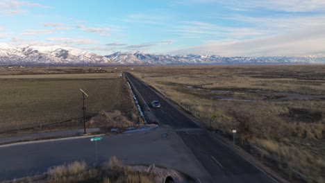 Rückwärtsflug-über-Die-Straße-In-Syracuse,-Utah,-Mit-Atemberaubender-Aussicht-Und-Felsigen-Bergen-Als-Hintergrund