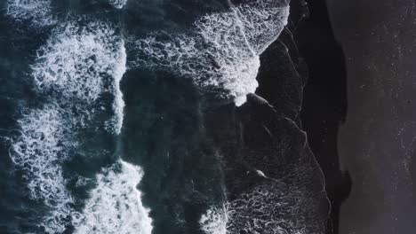 Aerial-top-down-view-of-water-waves-reaching-the-black-sand-beach-in-Keramas,-Bali