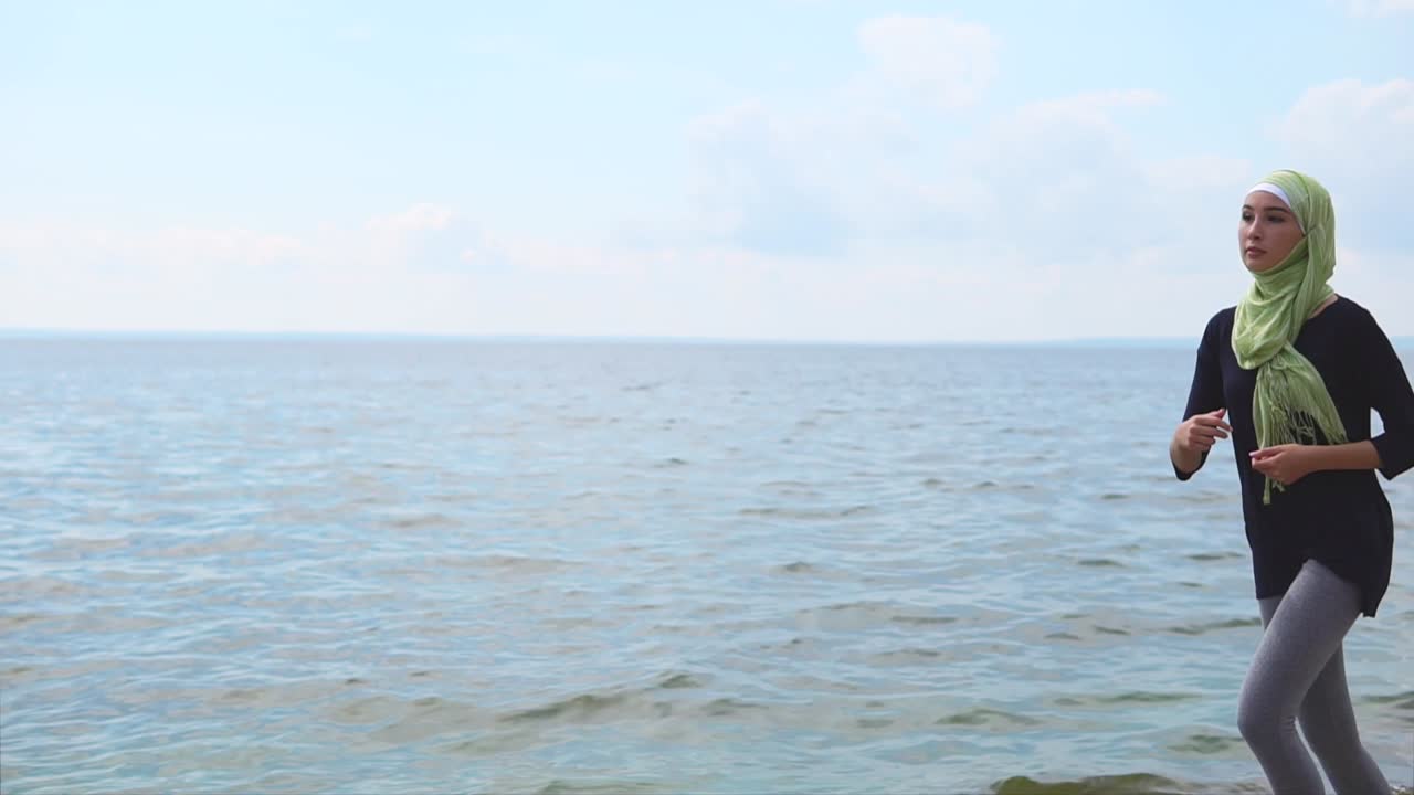 해변에서 달리는 무슬림 여성