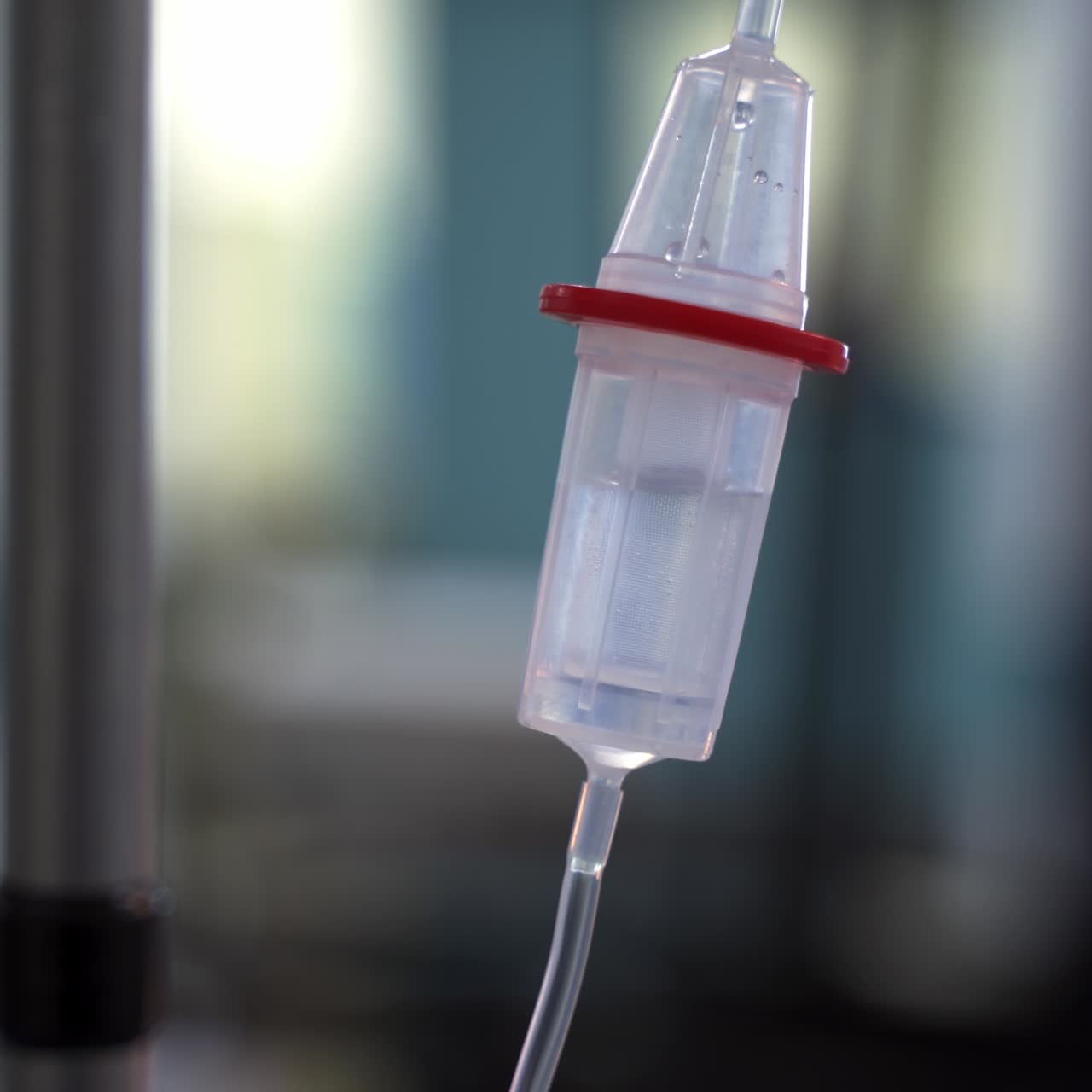 Transparent dropper with medical liquid dribbling down in hospital ward. Drop counter with medicine close up. Blurred backdrop