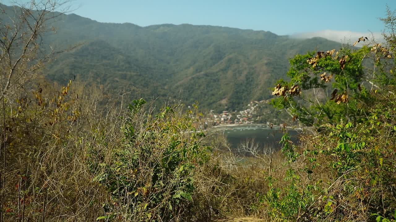 Ampia vista della baia di Yelapa con spiaggia e villaggio incorniciata da vegetazione secca e montagne in Jalisco, Messico