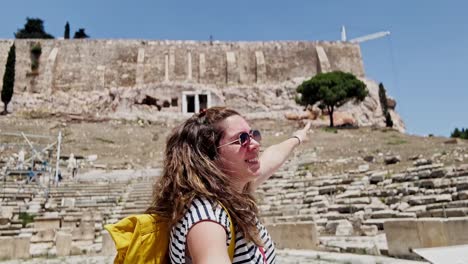 woman showing the view of an ancient greek amphitheatre, athens, greece