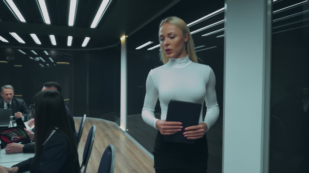 деловая женщина входит в комнату и разговаривает с партнерами.