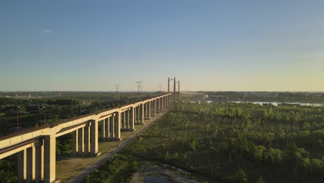 Aerial-orbital-of-Zarate-Brazo-Largo-road-and-railway-complex-cable-stayed-bridge-between-Entre-Rios-green-fields-at-golden-hour,-Argentina