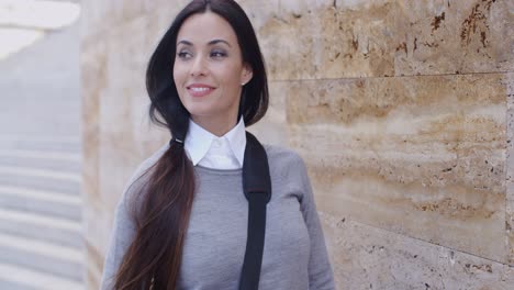 Confident-young-woman-leaning-against-wall