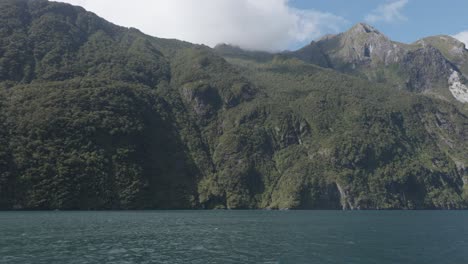 amplia vista del fiordo y las montañas desde un barco durante un soleado día de verano en milford sound, fiordland, nueva zelanda