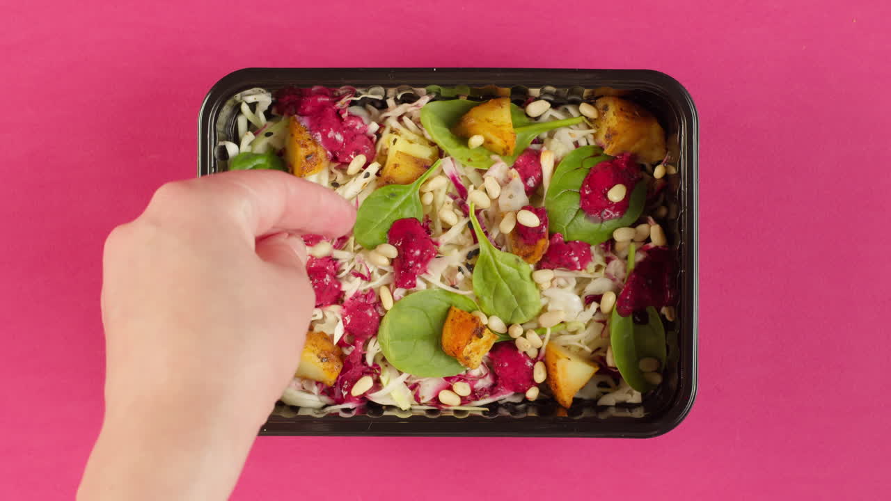 Mão Polvilhando Pinhões em uma Salada Fresca e Saudável