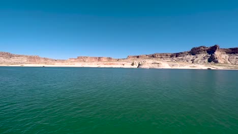 pan across the sandstone buttes from the turquoise waters of the shore of lake powell, page arizona