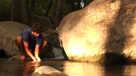 mediumshot of a hiker washing his face in a mountain pool