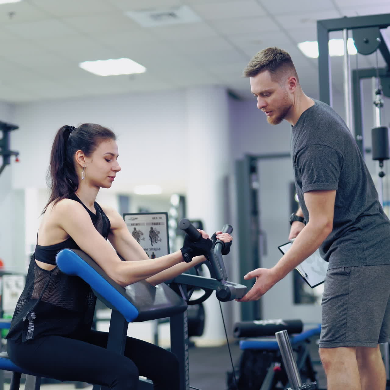 Beautiful athletic young woman making exercise at the gym. Exercises for biceps. Personal training.