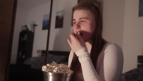 joven absorta en una película humorística y un delicioso cubo de palomitas de maíz