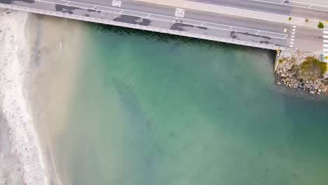 Drohnenblick-Auf-Den-Hundestrand-Von-Delmar,-Langsamer-Schwenk-über-Die-Straße-Mit-Grünem-Wasser