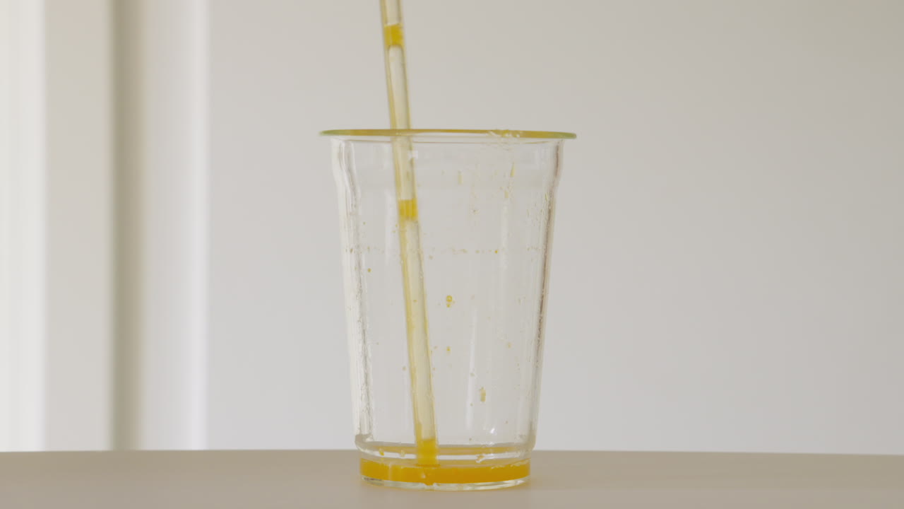 Succo d'arancia rinfrescante in un bicchiere rapidamente aspirato attraverso una cannuccia di vetro