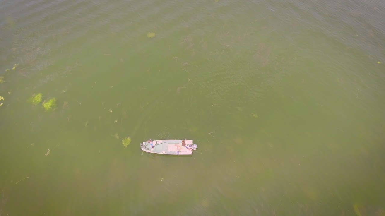 Two men fishing on a small boat in the middle of a lake