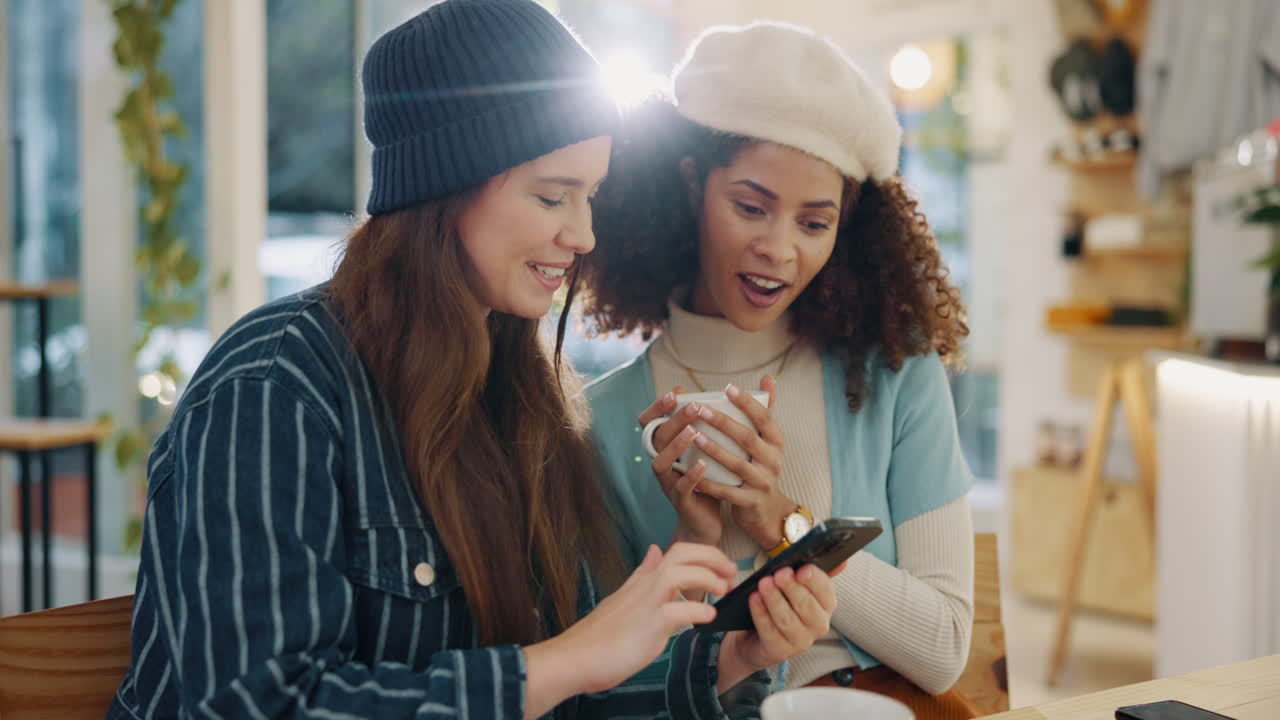 Two friends looking at a smartphone in a cafe