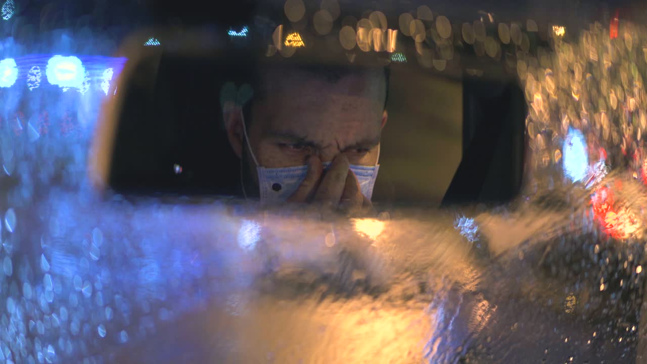 차에 앉아있는 남자가 의료 마스크를 착용했습니다.