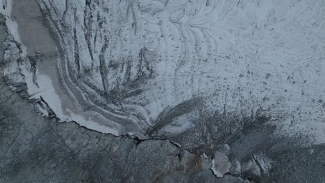 As-the-drone-elevates,-the-glacier-below-unravels-its-majestic-tapestry-of-frozen-formations,-shimmering-under-the-soft-light