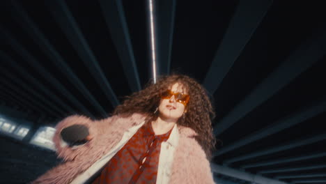 stylish girl performing dance on camera under urban overpass