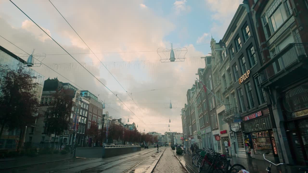 Morning view of Rokin in Amsterdam featuring tram tracks, bicycles, and a blend of modern and traditional buildings. The calm urban atmosphere is highlighted under a pastel sky. Amsterdam, Nederland