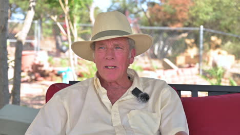 interesting guy senior man baby boomer sits outdoors, talking to someone, casual clothing wearing hat