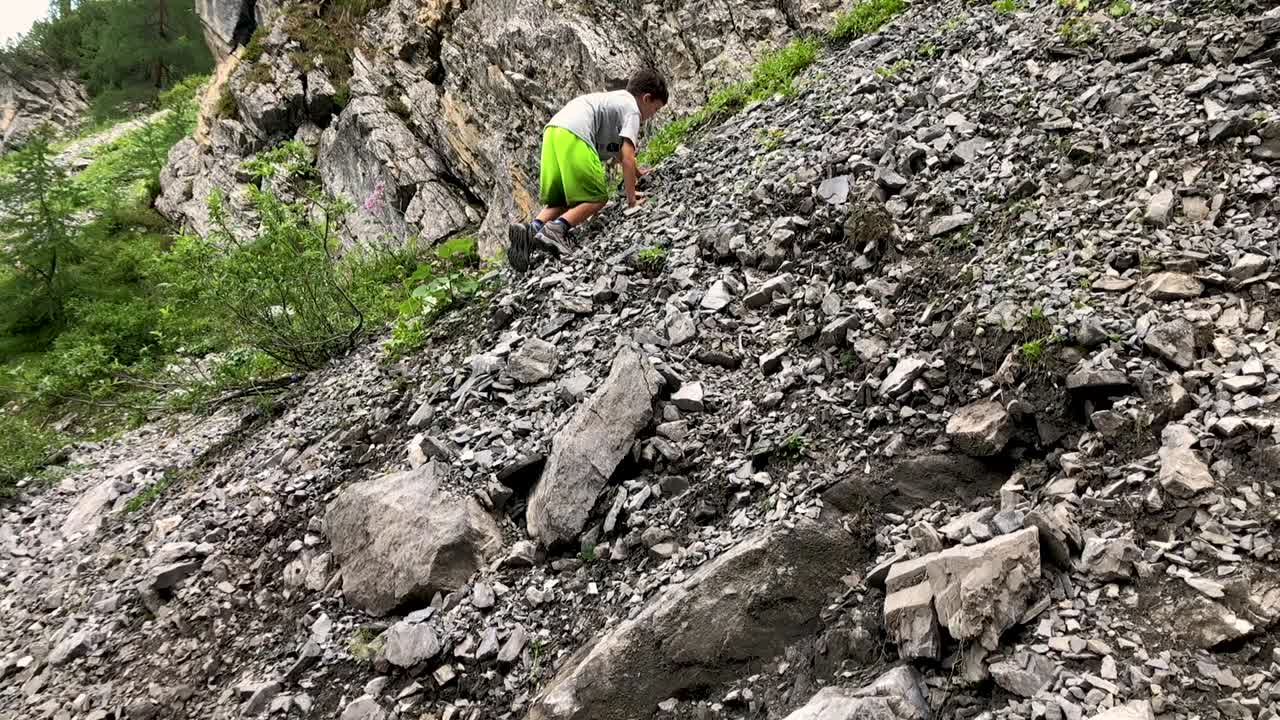 Cute young boy trying to climb mountain full of rubble