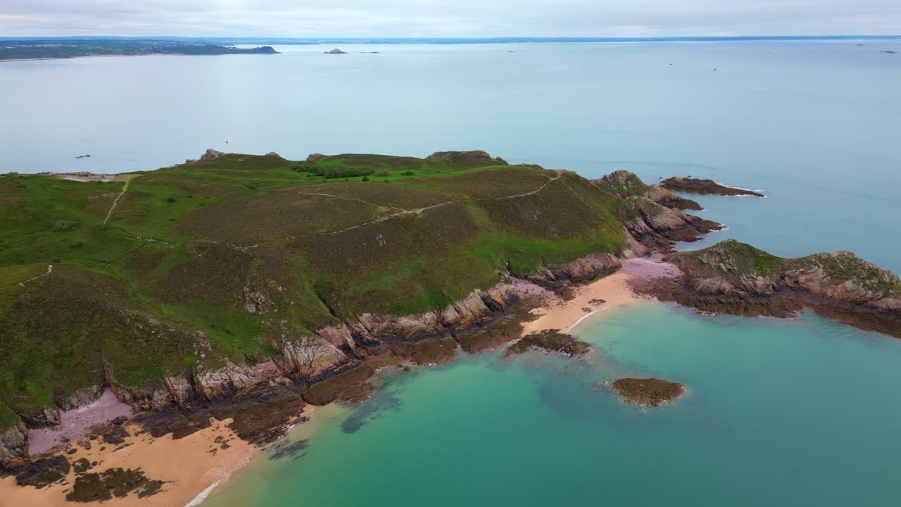 Aerial drone view of the Cap d'Erquy peninsula, featuring sandy beaches, green heathland, and tranquil turquoise sea in Brittany, France