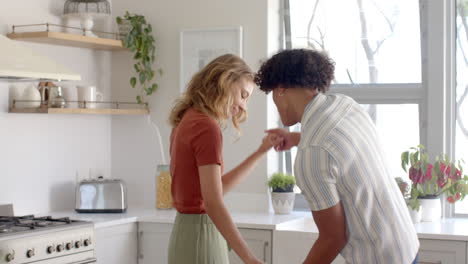 diverse couple dancing playfully in bright kitchen, enjoying morning together at home