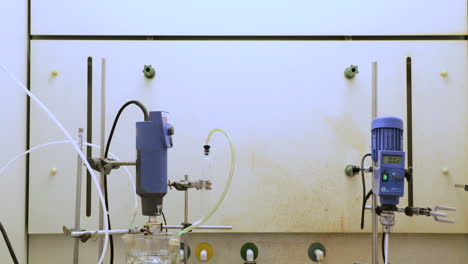 dos máquinas que mezclan soluciones químicas mientras se enfrían en hielo para un experimento - tiro inclinado hacia abajo