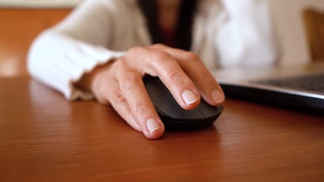 woman hand clicking computer mouse on top of wooden table