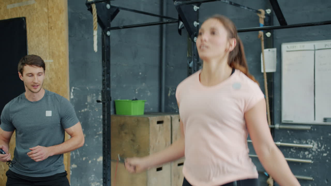 Woman Jumping Rope with Personal Trainer in Gym