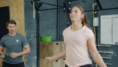 woman jumping rope with personal trainer in gym