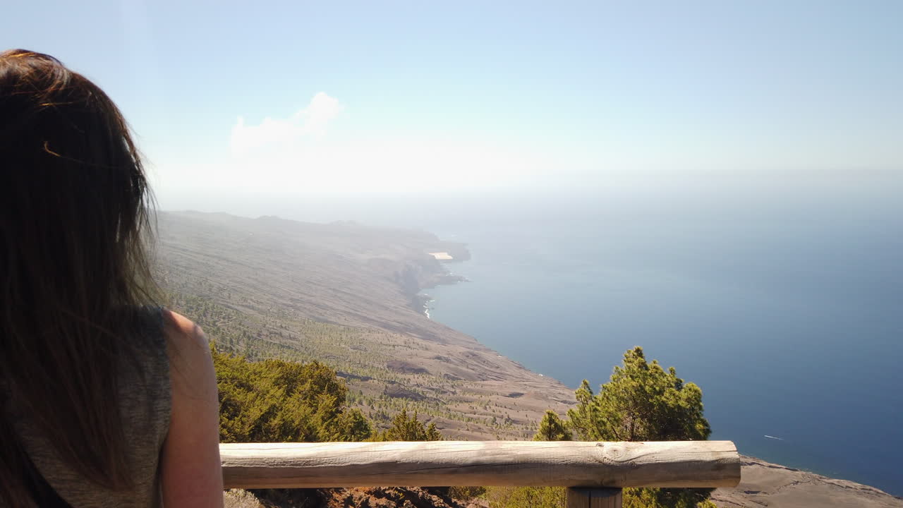 woman contemplating the vast ocean and coastline from a scenic viewpoint on El Hierro island