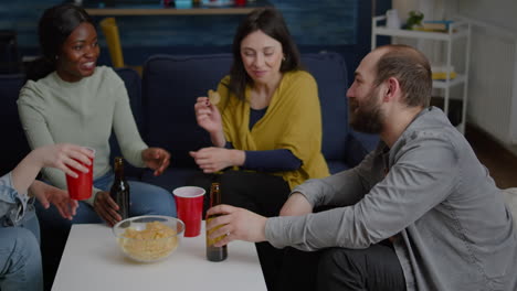 multi-cultural friends socializing while sitting on sofa in living room late at night