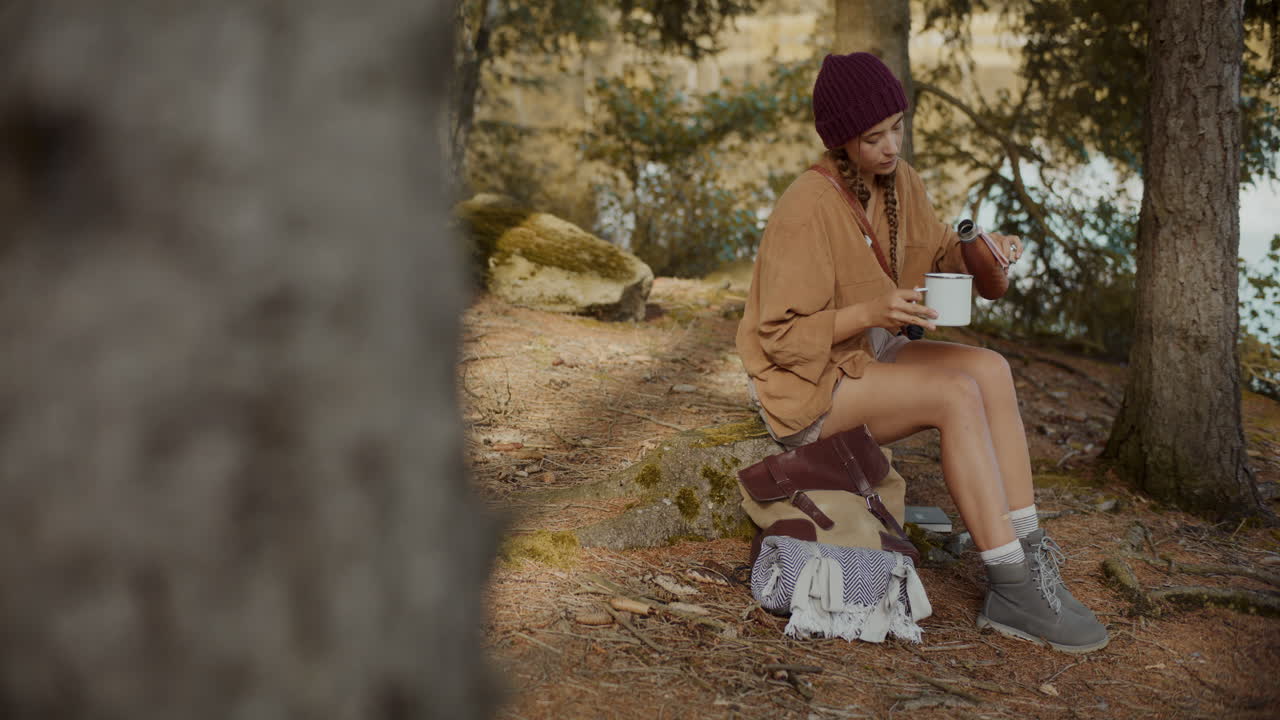 젊은 여성 관광객이 컵에 물을  ⁇ 고 있습니다.