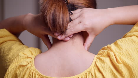 close-up shot of a woman massaging her nape using her hands and fingers to relieve the tension and stress that she is feeling