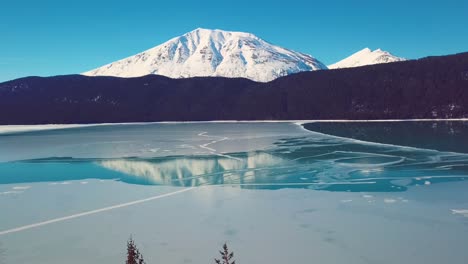 4k drone video of snow covered lakeside mountains in alaska during winter