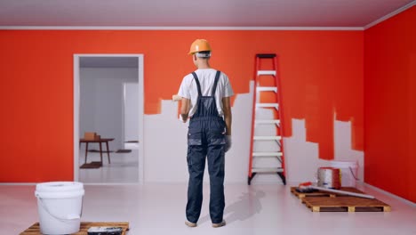 full body of back view asian man painter wearing safety helmet painting with painting wall in room