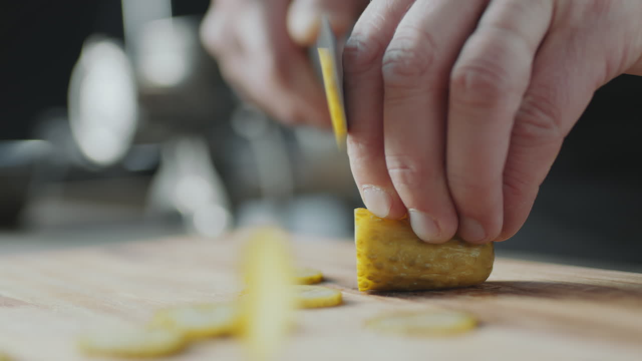 las manos del chef cortando pepinillos de eneldo