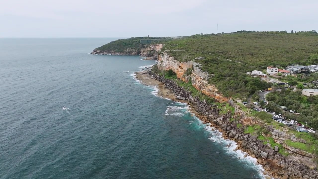 Avustralya'nın Sidney Doğu Banliyöleri'ndeki Clovelly Plajı yakınında, dramatik kumtaşı kayalıkları ve engebeli Pasifik kıyı şeridinin sakin bir günde çekilmiş havadan drone görüntüsü.