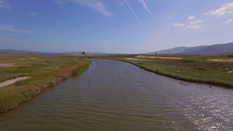 aerial: a river delta with a road-bridge passing through and some agricultural buildings