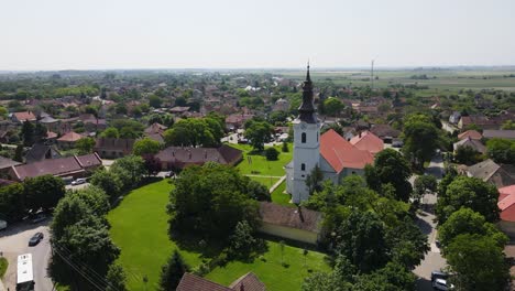 Drone-View-of-Reformed-Church-Surrounded-by-Greenery-in-Szalkszentmarton,-Hungary