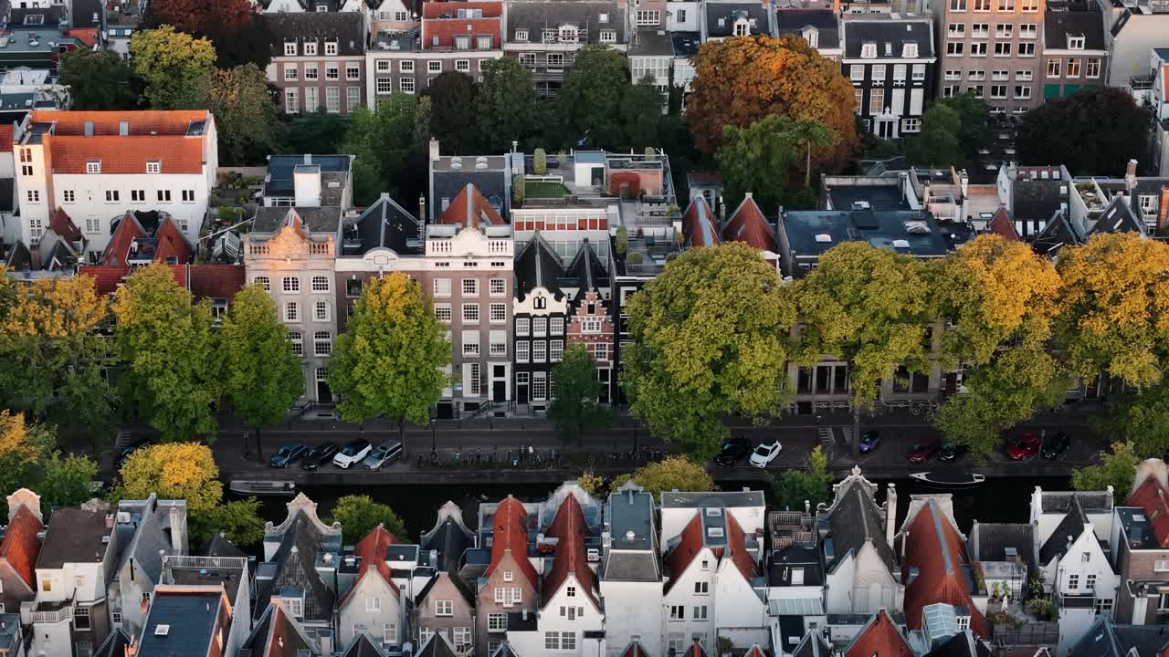 Sunrise approach above Amsterdam’s canals and sunlit historic rooftops