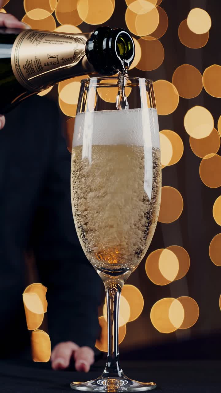 Primo piano video di champagne versato in un bicchiere, con luci bokeh sullo sfondo